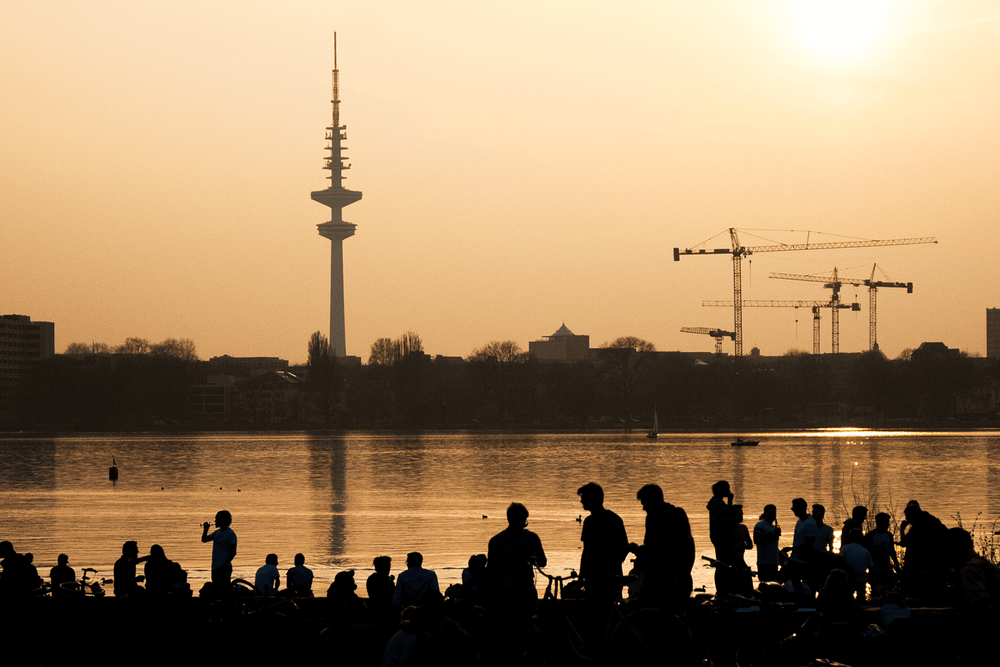 Junge Menschen an der Hamburger Außenalster. Im Hintergrund Baukräne.